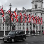 מונית שחורה בלונדון על רקע דגלי אנגליה