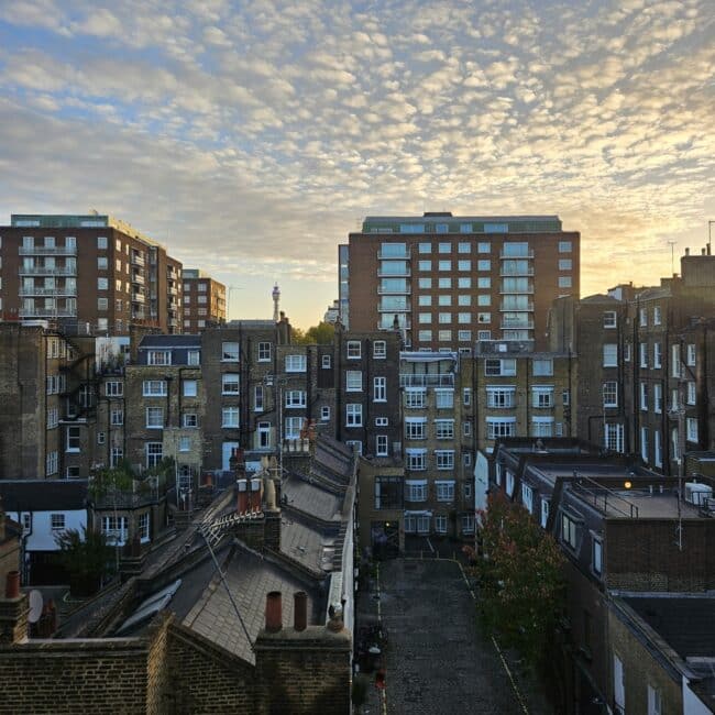 הנוף הנשקף מהחדר בקומה החמישית: מבט אל גגות לונדון ונוף עירוני קסום עם אור שקיעה רך