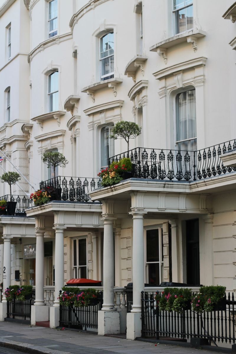 Victorian-style white buildings with floral balconies on a London street.